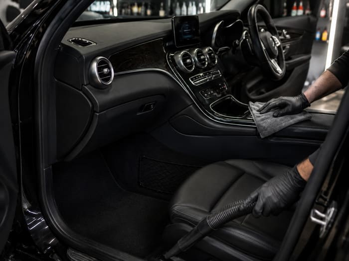 Interior detail — wiping down dashboard and vacuuming seats